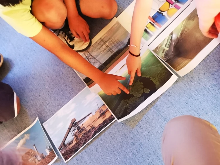 Das Foto zeigt Kinderh&auml;nde, die auf dem Boden gemeinsam verschiedene Bildkarten betrachten und vergleichen.