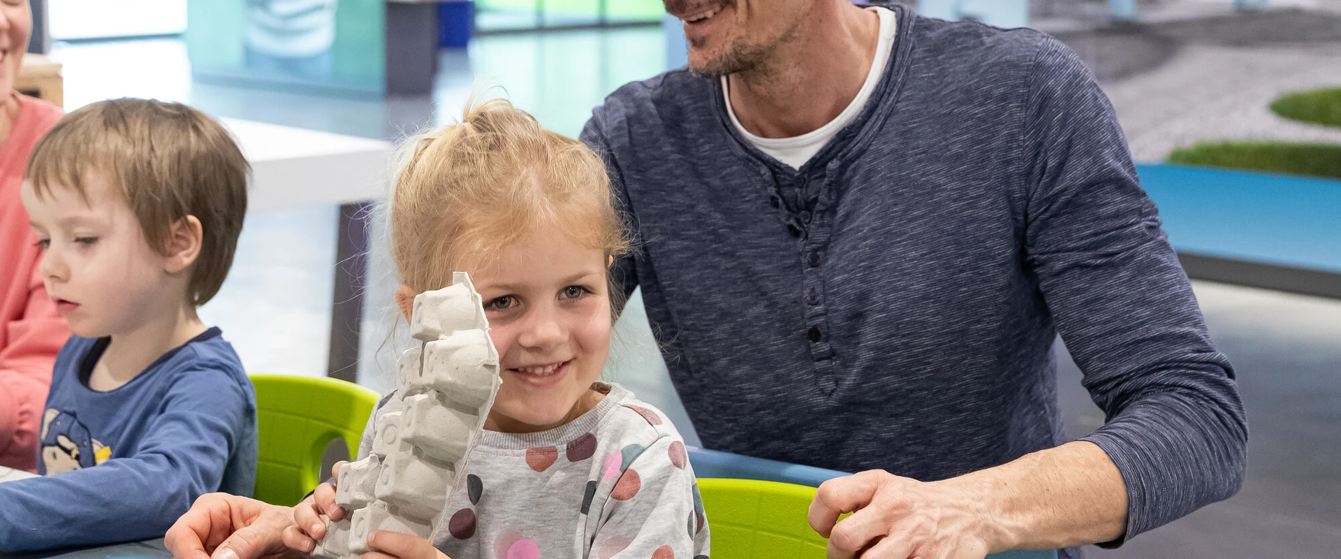 Kinder mit Vater basteln in der Kreativwerkstatt.