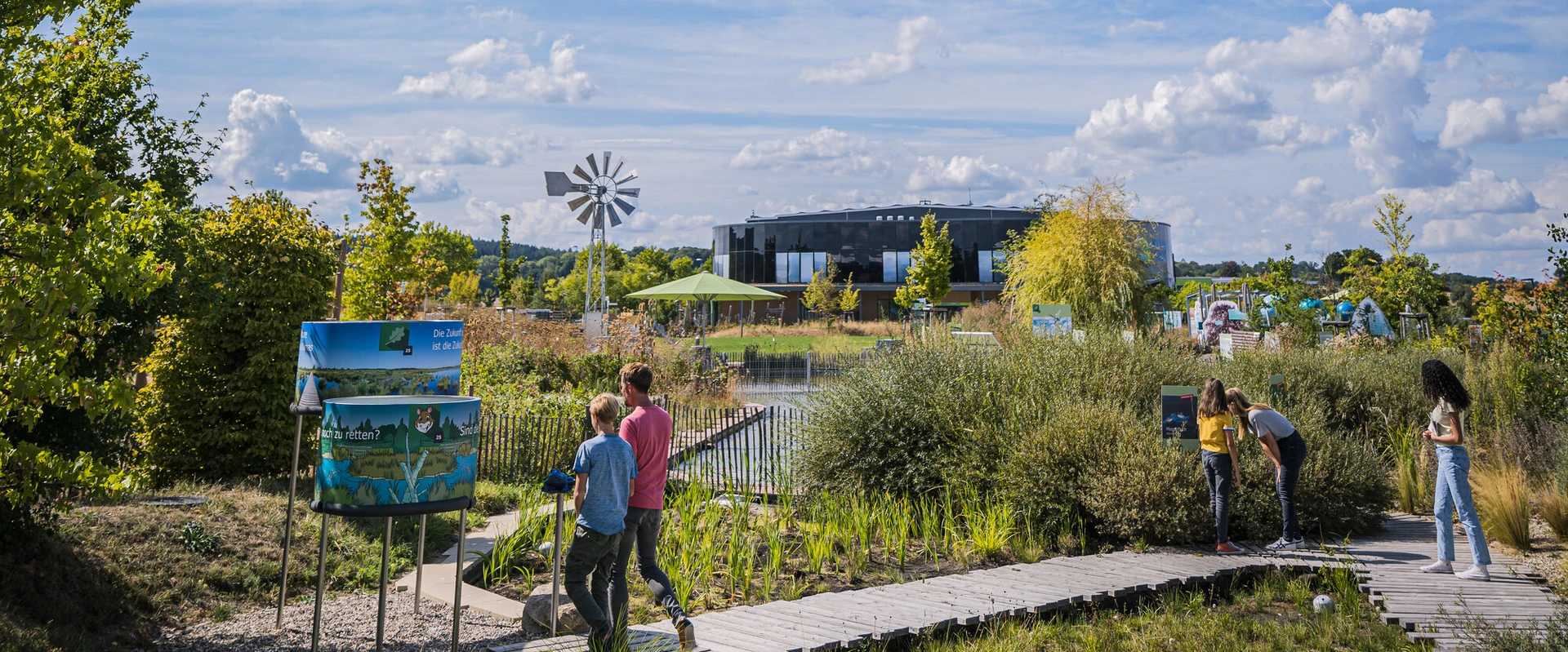Familie schlendert durch das angelegte Moor und betrachtet Infotafeln.